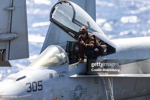 Flight deck crew member inspects an F/A-18 Super Hornet fighter jet aboard the USS Dwight D. Eisenhower aircraft carrier during operations in the...