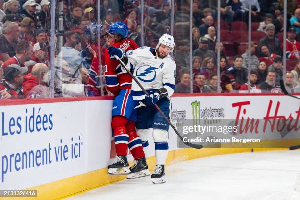 Nikita Kucherov of the Tampa Bay Lightning hits Kaiden Guhle of the Montreal Canadiens into the boards during the first period of the NHL regular...