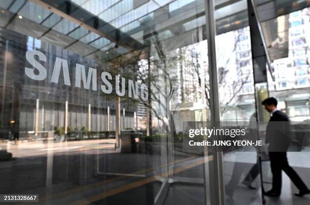 Man walks past the Samsung logo displayed on a glass door at the company's Seocho building in Seoul on April 5, 2024. Samsung Electronics said on...