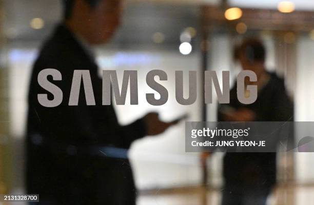 People walk past the Samsung logo displayed on a glass door at the company's Seocho building in Seoul on April 5, 2024. Samsung Electronics said on...