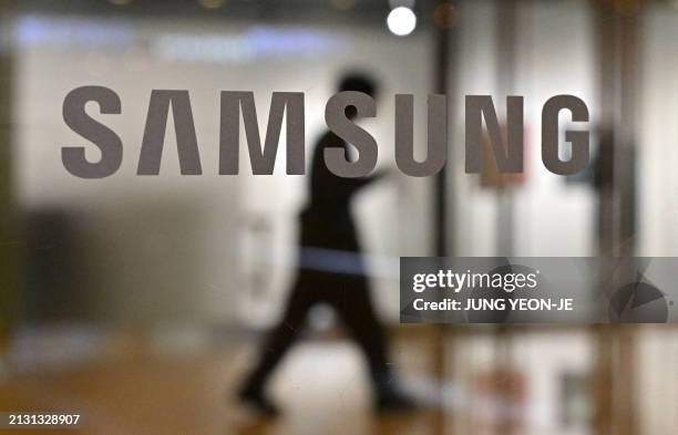 Man walks past the Samsung logo displayed on a glass door at the company's Seocho building in Seoul on April 5, 2024. Samsung Electronics said on...