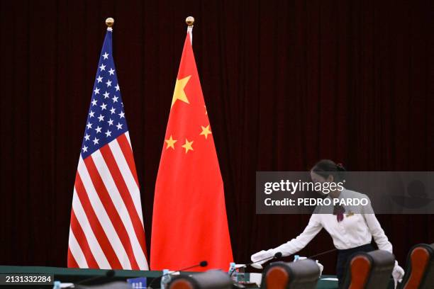 An assistant stands next to China's and USA's flags before a meeting between US Treasury Secretary Janet Yellen and China's Vice Premier He Lifeng at...