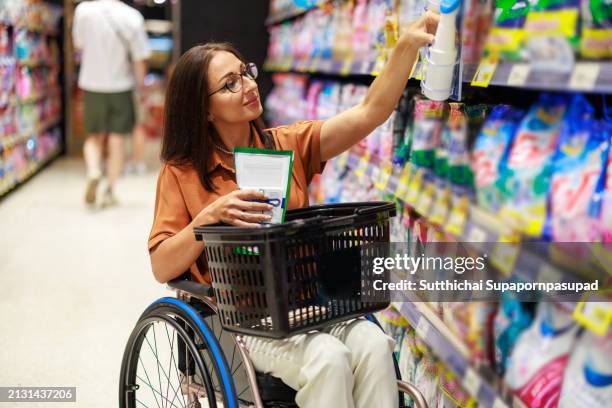 independent grocery shopping: caucasian disabled woman in wheelchair selecting fresh product at supermarket. - chonburi province stock pictures, royalty-free photos & images