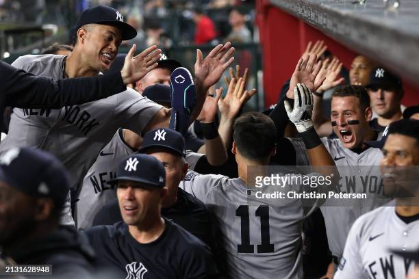 Anthony Volpe of the New York Yankees high fives Anthony Rizzo and Giancarlo Stanton in the dugout after scoring a run against the Arizona...
