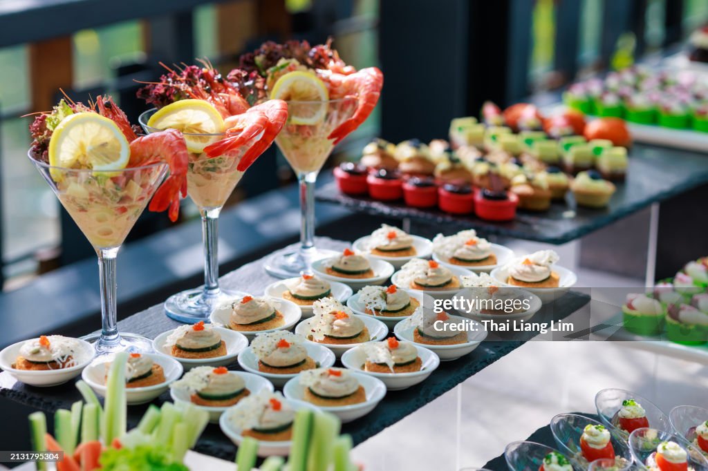 Various sweet desserts, appetizers, and finger foods are arranged on a buffet table, ready for party guests to enjoy.