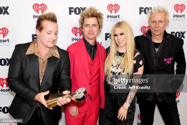 Tré Cool, Billie Joe Armstrong and Mike Dirnt of Green Day, winners of the Landmark Award, pose in the press room with Avril Lavigne during the 2024...