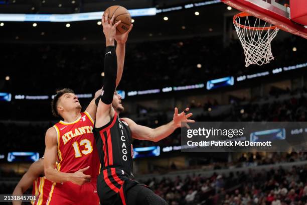 Bogdan Bogdanovic of the Atlanta Hawks blocks a shot by Alex Caruso of the Chicago Bulls during the second half at the United Center on April 01,...