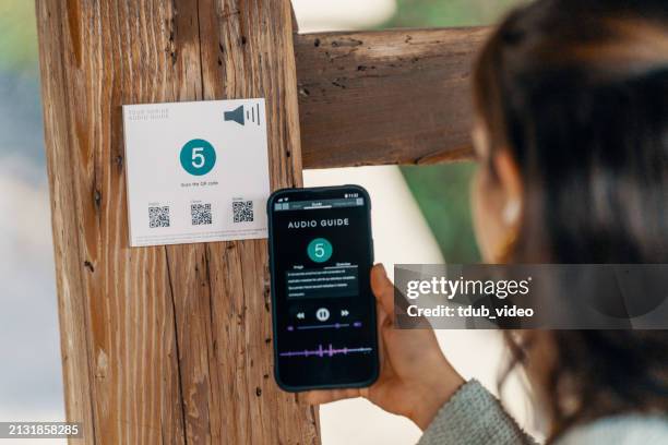 mid adult woman using a multilingual audio guide smartphone app while visiting a japanese shrine - multilingual stock pictures, royalty-free photos & images
