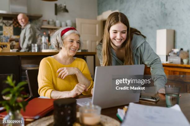 happy girl teaching grandmother to use laptop at home - bonding icon stock pictures, royalty-free photos & images