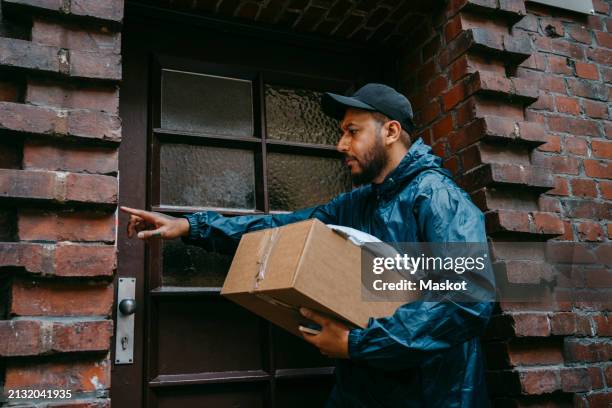 male courier delivery person ringing doorbell while arriving with package outside house - side hustle stock pictures, royalty-free photos & images