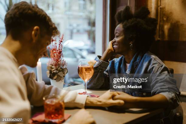 boyfriend holding hand and flirting with girlfriend during date at restaurant - namoro pela internet imagens e fotografias de stock