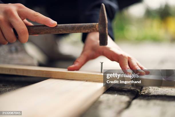 teenage boy is driving nail with a hammer - spijker stockfoto's en -beelden