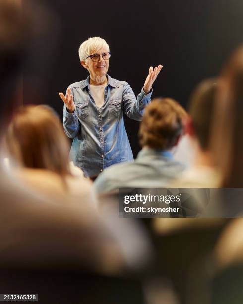 senior public speaker talking on a conference at convention center. - orador público fotografías e imágenes de stock