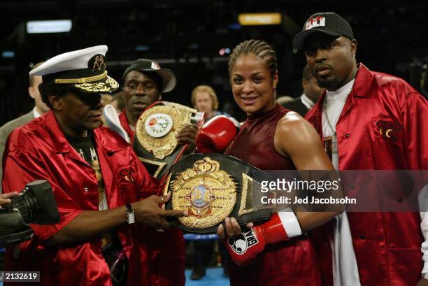 Laila Ali smiles as she holds her IBA title belt with trainer Roger Mayweather after defeating Valerie Mahfood in the women's super middleweight bout...