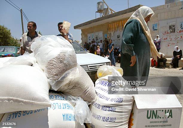 Palestinians wait to receive their ration of food aid from UNRWA staff July 2, 2003 in the West Bank town of Bethlehem. UNRWA, the United Nations...