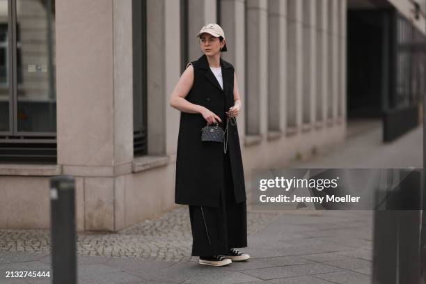 Maria Barteczko seen wearing Ray-Ban gold round retro glasses, gold earrings, Bershka beige baseball cap, WENDYKEI black long sleeveless vest,...