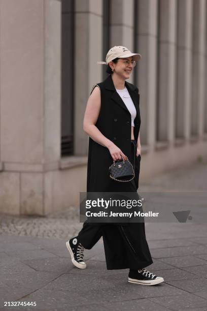 Maria Barteczko seen wearing Ray-Ban gold round retro glasses, gold earrings, Bershka beige baseball cap, WENDYKEI black long sleeveless vest,...