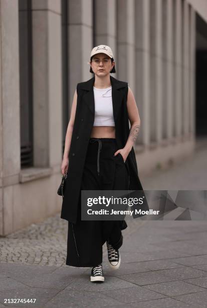 Maria Barteczko seen wearing Ray-Ban gold round retro glasses, gold earrings, Bershka beige baseball cap, WENDYKEI black long sleeveless vest,...