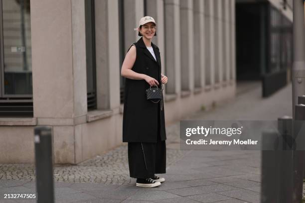 Maria Barteczko seen wearing Ray-Ban gold round retro glasses, gold earrings, Bershka beige baseball cap, WENDYKEI black long sleeveless vest,...