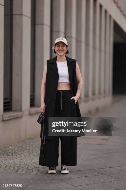 Maria Barteczko seen wearing Ray-Ban gold round retro glasses, gold earrings, Bershka beige baseball cap, WENDYKEI black long sleeveless vest,...