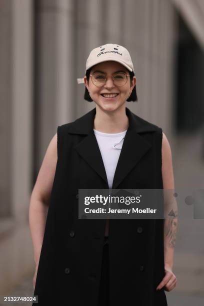 Maria Barteczko seen wearing Ray-Ban gold round retro glasses, gold earrings, Bershka beige baseball cap, WENDYKEI black long sleeveless vest,...