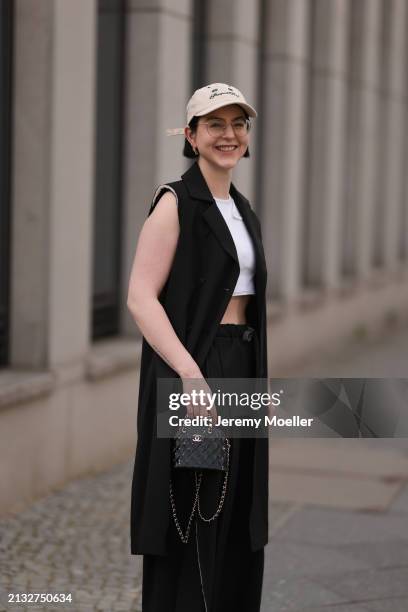 Maria Barteczko seen wearing Ray-Ban gold round retro glasses, gold earrings, Bershka beige baseball cap, WENDYKEI black long sleeveless vest,...