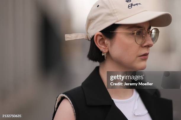 Maria Barteczko seen wearing Ray-Ban gold round retro glasses, gold earrings, Bershka beige baseball cap, WENDYKEI black long sleeveless vest,...