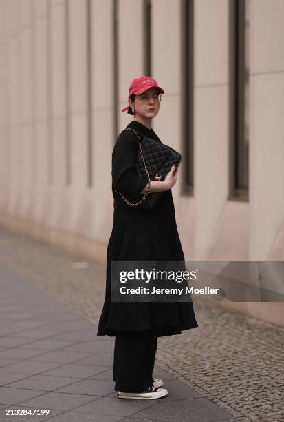 Maria Barteczko seen wearing Ray-Ban gold round retro glasses, Pull&Bear red vintage baseball cap, WENDYKEI black wrinkled oversized midi dress,...