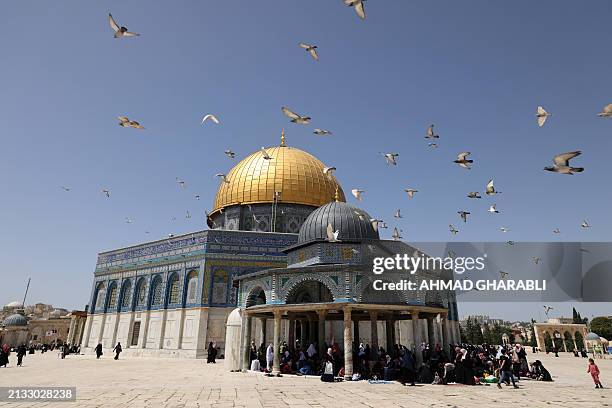 Flock of pigeons flies in front of the Dome of the Rock shrine at the Al-Aqsa mosque compound in Jerusalem, as people gather before the last Friday...
