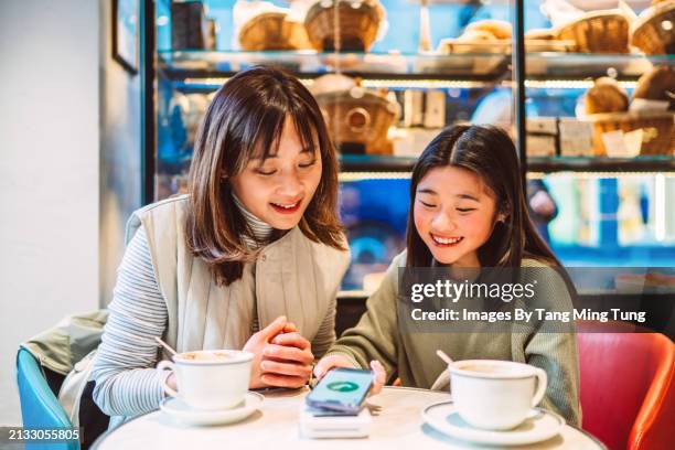 mother and daughter making contactless payment with smart phone in cafe joyfully - digital wallet stock pictures, royalty-free photos & images