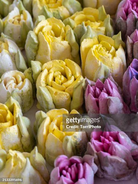 a close-up of colorful flower shaped marshmallows, arranged in rows on top of each other. tulip-shaped zefir in yellow and pink color in style of meringue cookies. zefir or zephyr edible flowers - gelatin powder stock-fotos und bilder