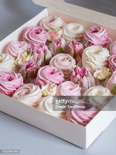 a white box containing pink and cream colored rosettes made from marshmallows, shaped like roses of different sizes stacked on top of each other. zephyr flowers confection - gelatin powder fotografías e imágenes de stock