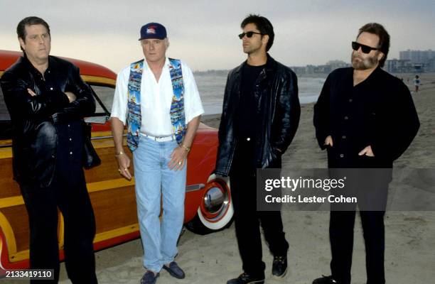American musicians Brian Wilson, Mike Love, actor John Stamos and musician Carl Wilson , of the American rock band The Beach Boys, talk at a beach in...