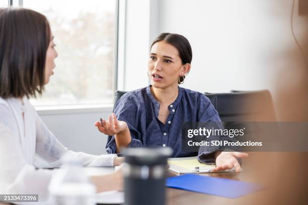 duas colegas de trabalho discordam durante reunião de equipe - envolvimento dos funcionários - fotografias e filmes do acervo