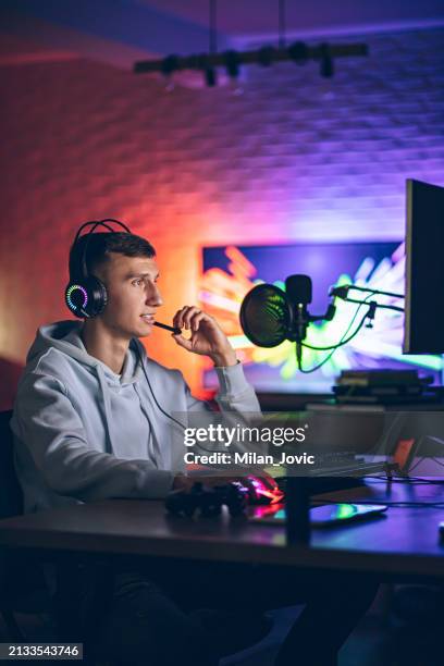 cybersport gamer having live stream game in room with neon lighting in background - difusão de televisão imagens e fotografias de stock