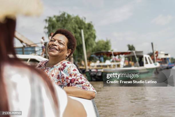 senior woman talking with friend during a boat trip at river - rondvaartboot stockfoto's en -beelden