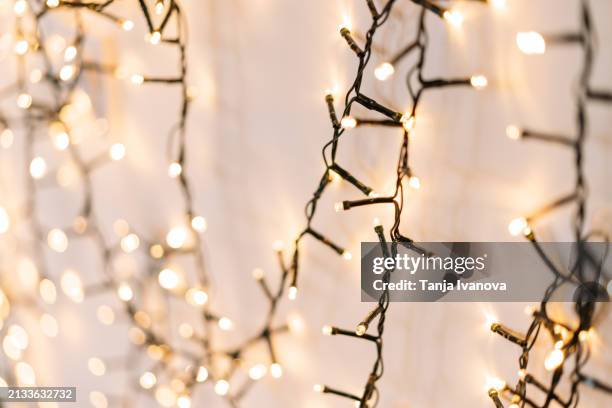 blurry festive christmas background with glowing garlands of lights. concept of new year celebration. copy space - cadena de luces fotografías e imágenes de stock