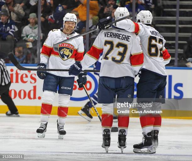 Brandon Montour of the Florida Panthers celebrates a goal with teammates Sam Reinhart and Carter Verhaeghe against the Toronto Maple Leafs during the...