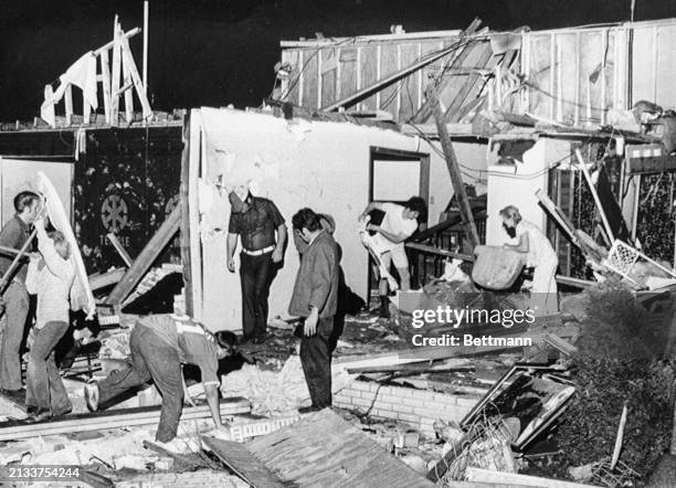 Family along with their neighbors climb through the debris of a home that was leveled as tornadoes ripped through portions of Nashville for the...