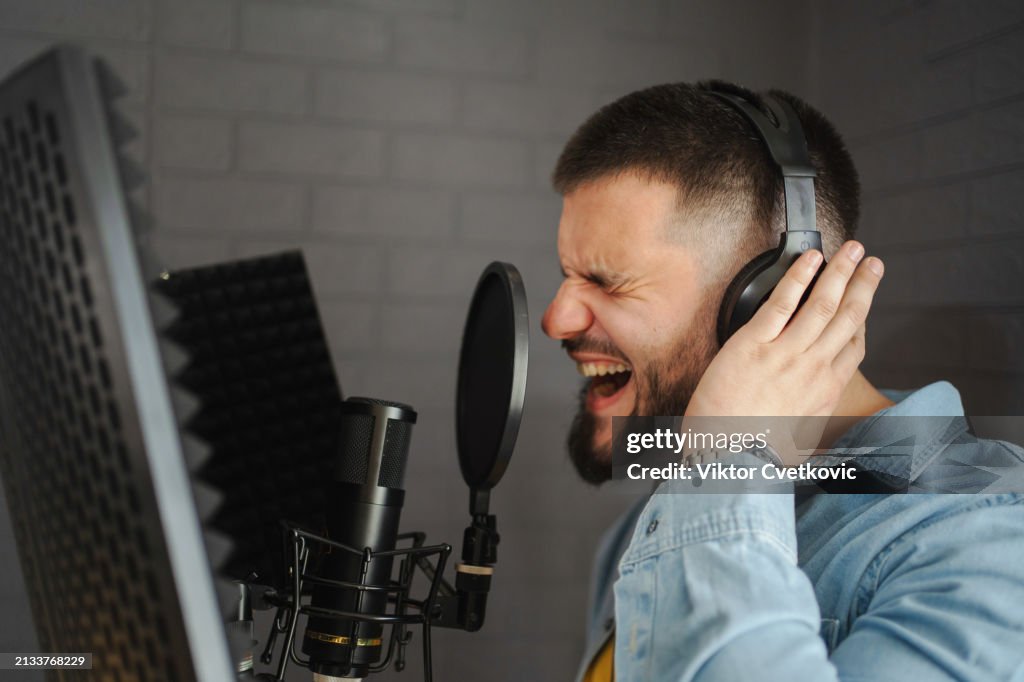 Caucasian male artist recording a song in the music studio