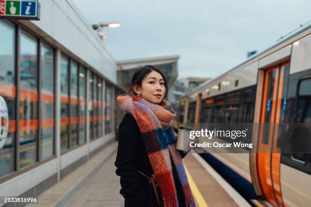 young asian woman waiting for the train on railway platform - london underground stock pictures, royalty-free photos & images