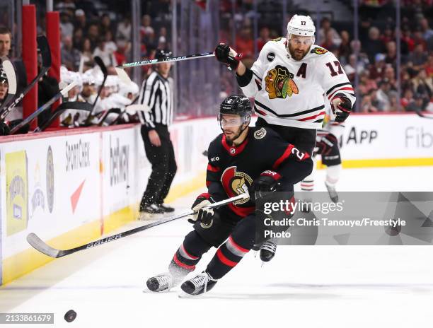 Nick Foligno of the Chicago Blackhawks jumps around Artem Zub of the Ottawa Senators as they skate for the puck during the third period at Canadian...