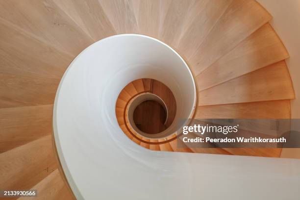 a contemporary spiral staircase with a flawless white balustrade and warm wooden steps. - spiral staircase stock pictures, royalty-free photos & images