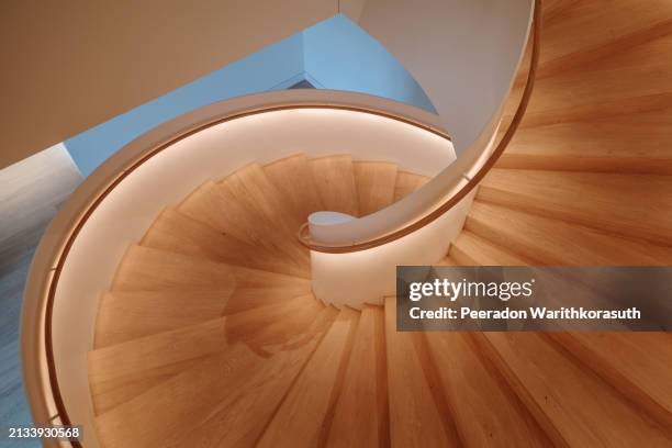 a contemporary spiral staircase with a flawless white balustrade and warm wooden steps. - abstract interior design photos et images de collection