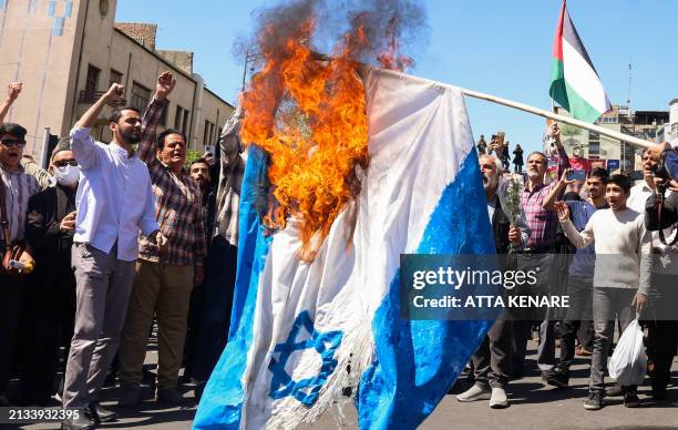 Demonstrators burn an Israeli flag during the funeral for seven Islamic Revolutionary Guard Corps members killed in a strike in Syria, which Iran...