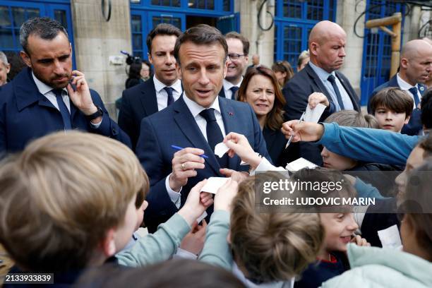 French President Emmanuel Macron signs autographs for children during a visit to the Ecole primaire d'application Blanche and the Laboratoire...