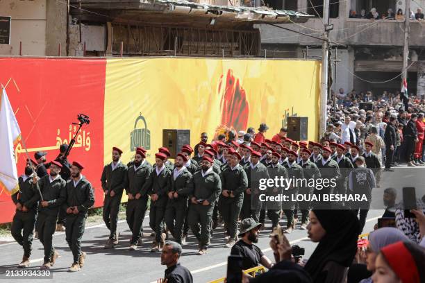 People watch as Palestinian members of a pro-Syrian government squad take part in a military parade to mark the annual Quds Day commemorations, in...