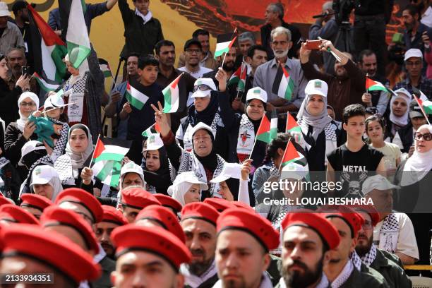 People watch as Palestinian members of a pro-Syrian government squad take part in a military parade to mark the annual Quds Day commemorations, in...