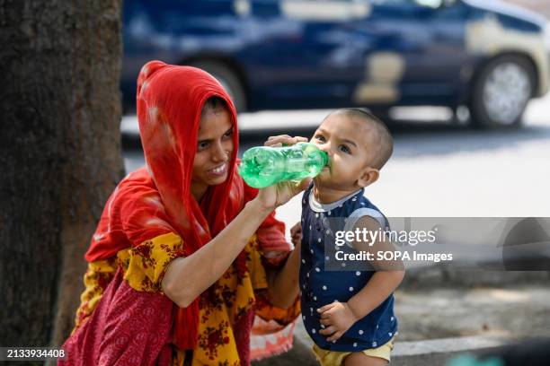 Mother gives water to her child during hot weather in Dhaka.