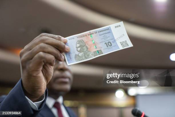 John Mushayavanhu, governor of Zimbabwe's central bank, holds up a new currency unit called ZiG during a news conference in Harare, Zimbabwe, on...